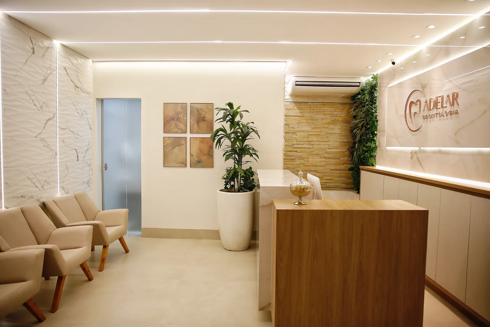Hall de entrada da Adelar Odontologia, com poltronas, parede de mármore claro e ar-condicionado